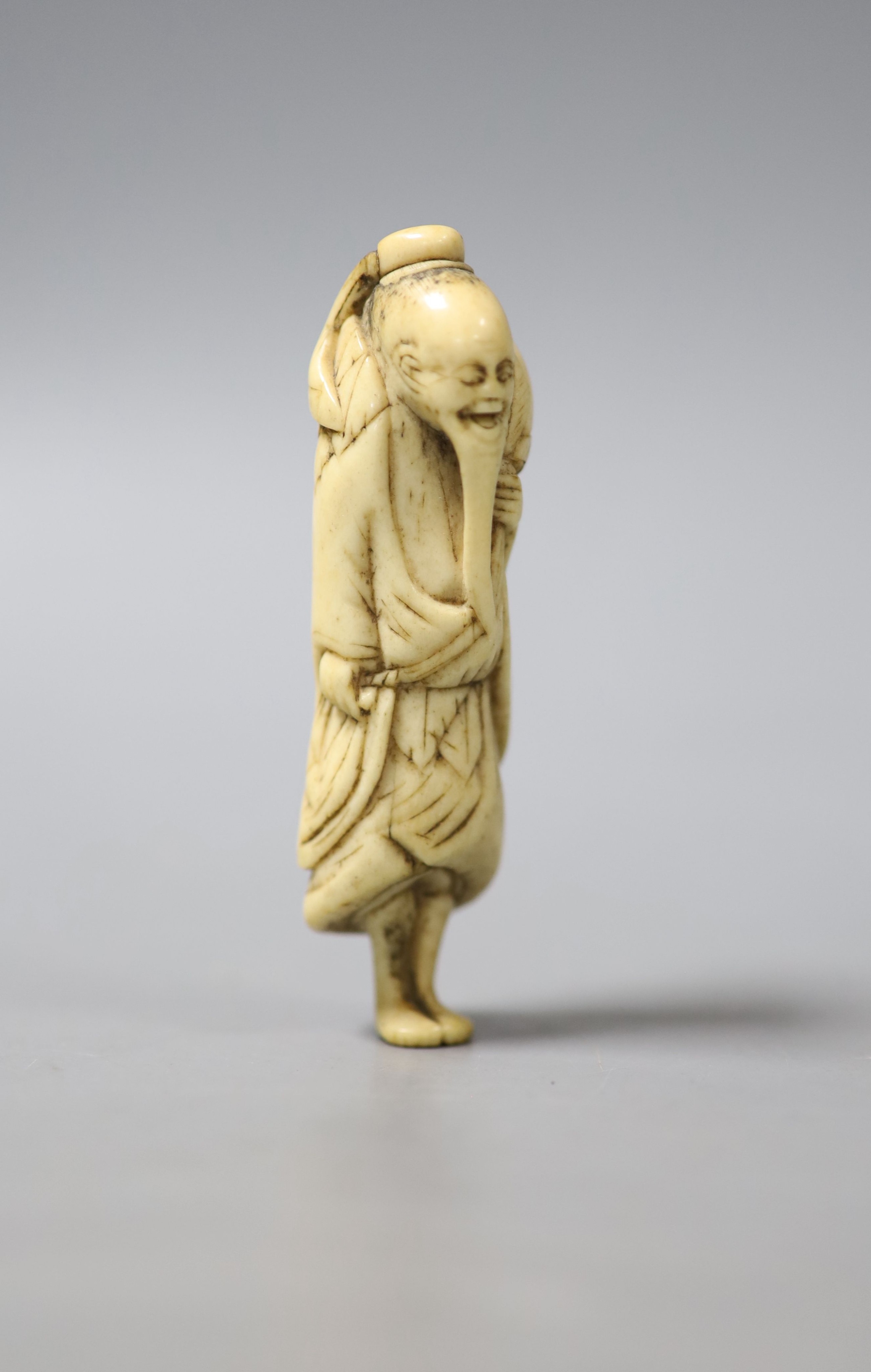 A late 18th/early 19th century Japanese carved stag antler netsuke modelled as a Sennin, 7.4 cm